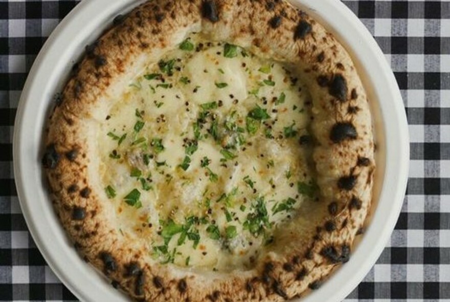 White pizza on a plate on gingham cloth.