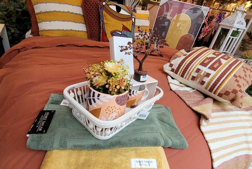 A selection of homewares displayed on a bed with rust-coloured manchester.