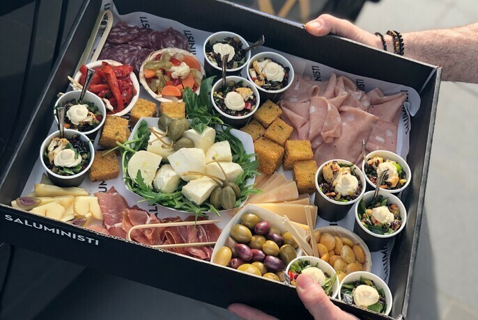 Tray of antipasto with cured meats, olives, various cheeses, and pickled vegetables.
