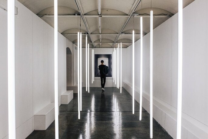 Person walking through a white walled gallery space.