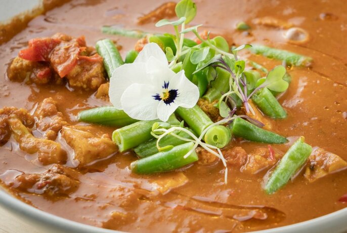 A thick stew with beans and a flower garnish. 