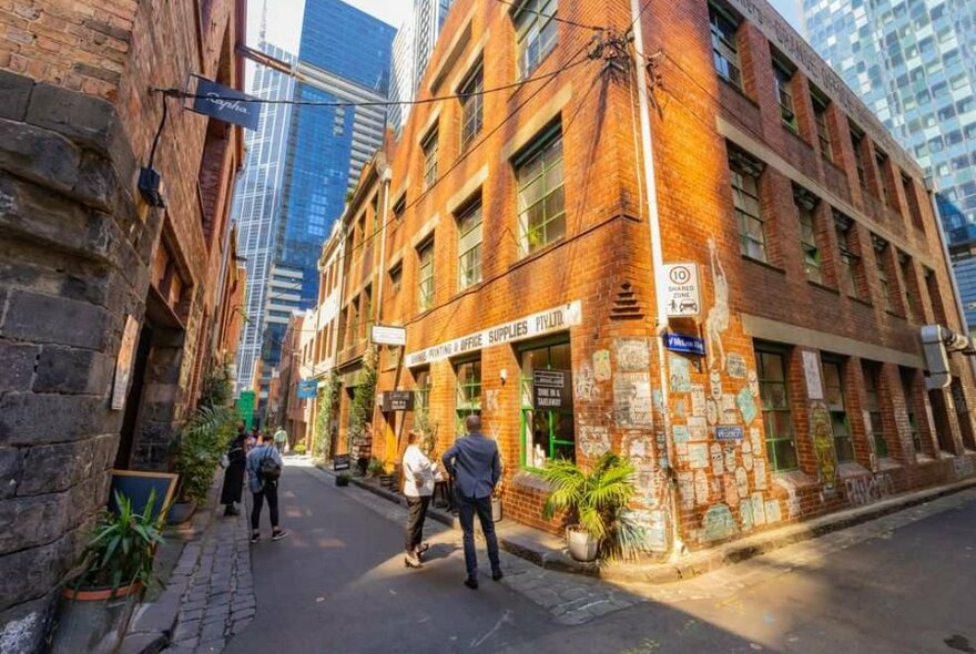 Two people standing outside a brick building in a laneway.