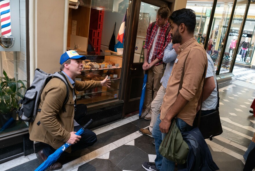 Tour guide talking with guests, indicating to a shopfront.