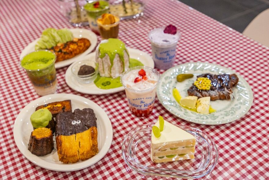A checked tablecloth with various dishes of pastries and cups.