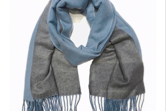 A blue and grey scarf looped together on a white background.