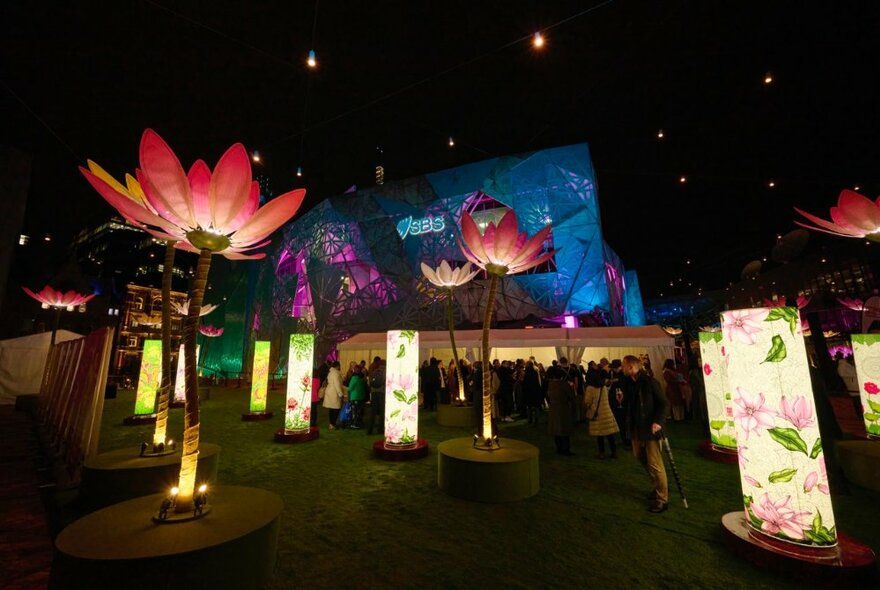 Light display of illuminated lotus artworks at night.
