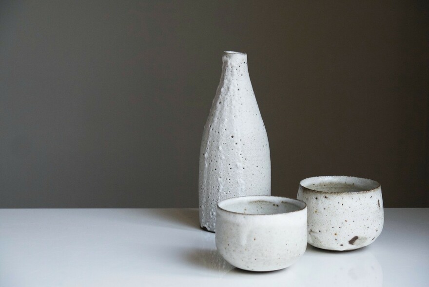 White ceramic Japanese sake bottle and two cups.