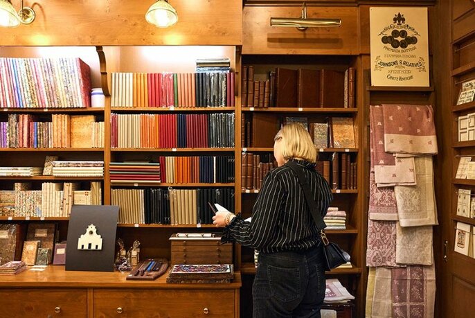 Person looking at a book with shelves of books in the background.