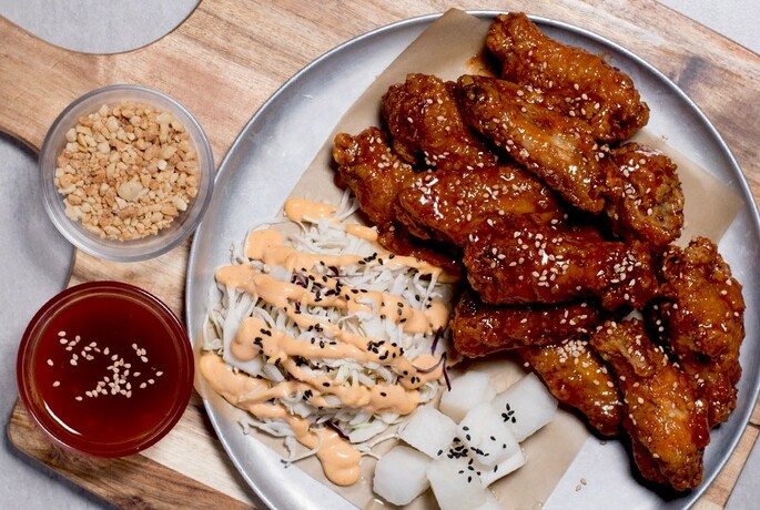 Plate of sesame chicken with condiments.
