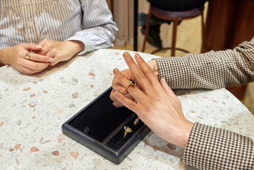 A woman trying on a sapphire engagement ring in a jewellery store. 