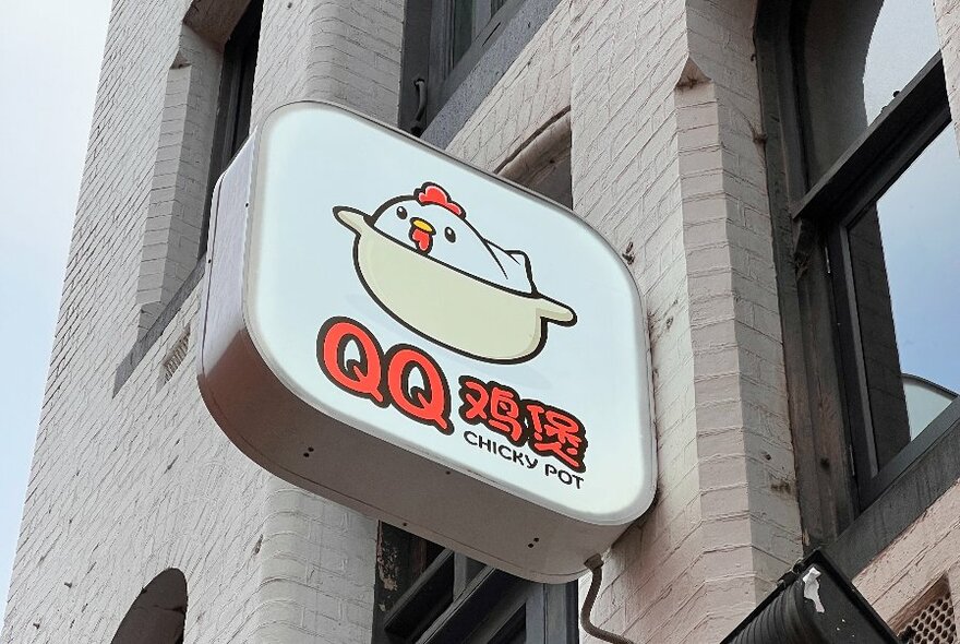 Exterior signage of QQ Chicky Pot attached to a brick wall.