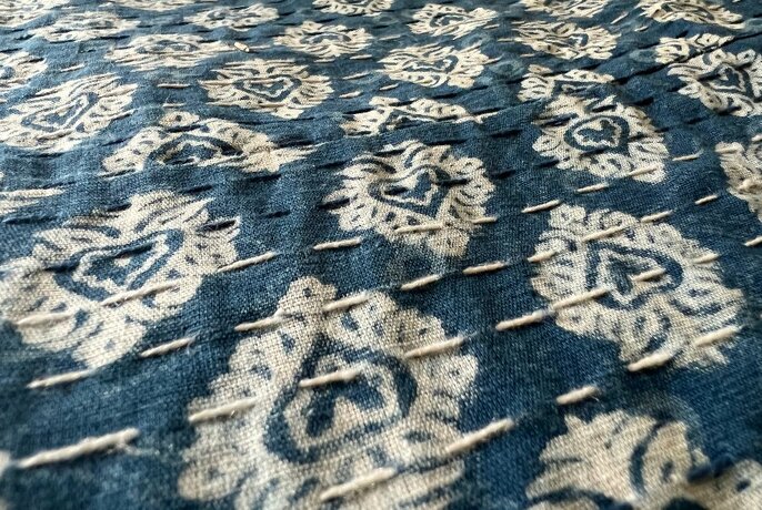 Vintage piece of blue and white patterned textile spread out on a table.