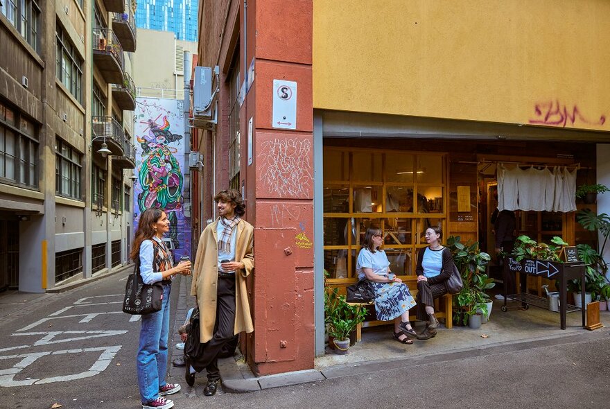 People hanging out outside a laneway cafe.