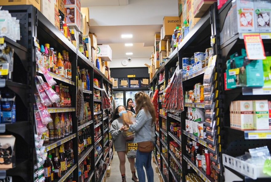 And interior aisle of the Thai Grocery Store with customers selecting products from the shelves.