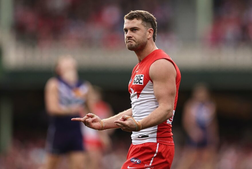 A Sydney Swans AFL football player pointing two fingers and grimacing.