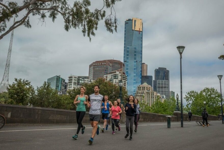Running tour jogging along a Yarra pathway with towers in the background.