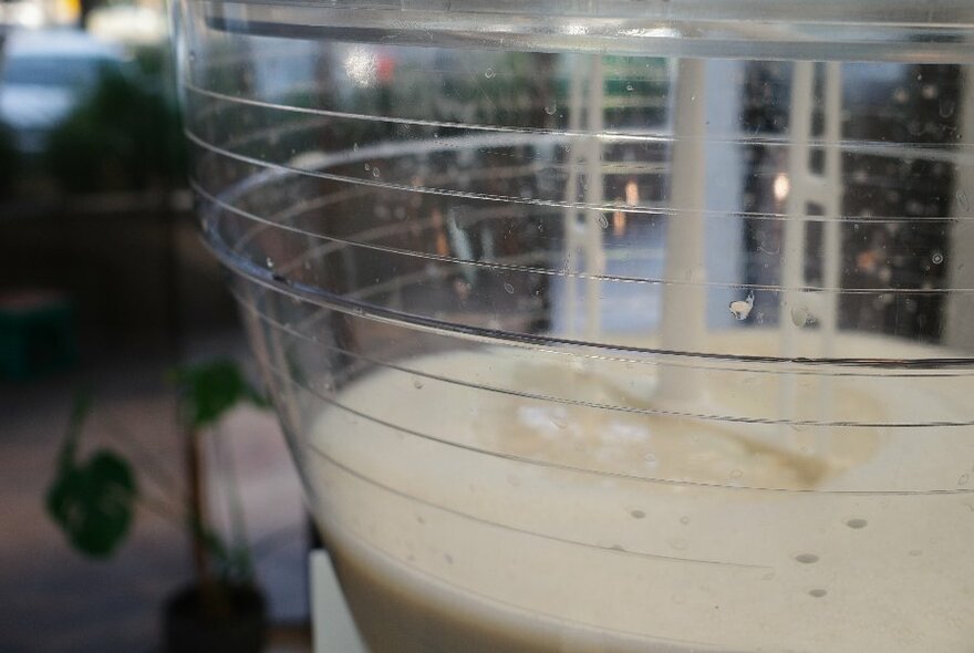 Close-up of cream-coloured liquid being churned in mixer.