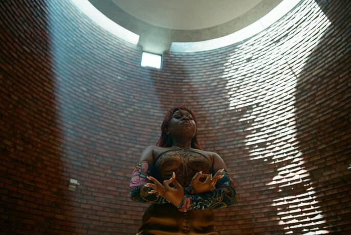 Artist Sampa the Great standing in a bricked circular well.