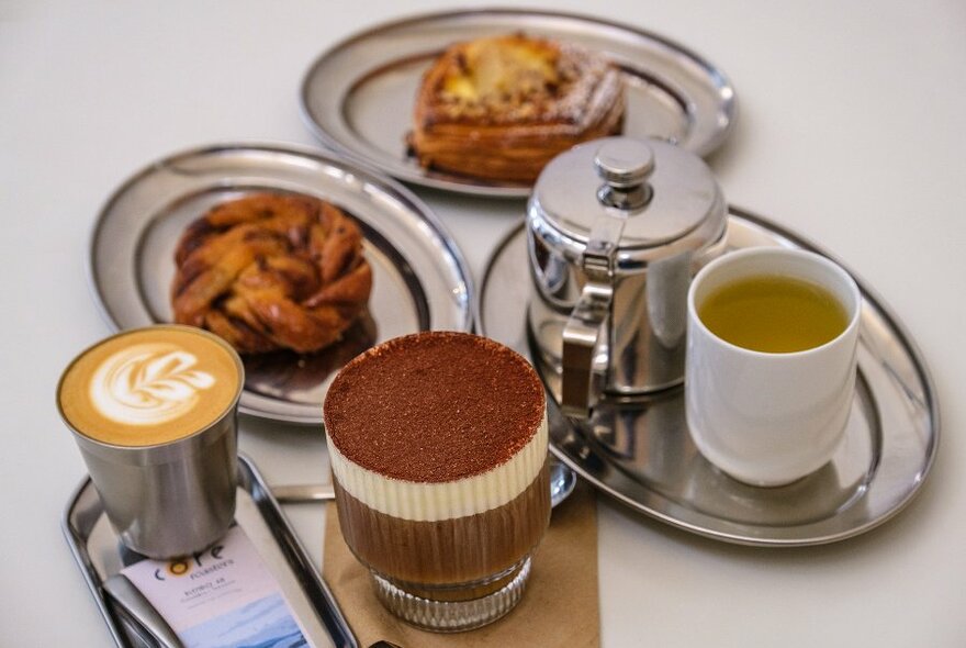 A selection of coffee, tea and pastries with a layered chocolate coffee drink. 