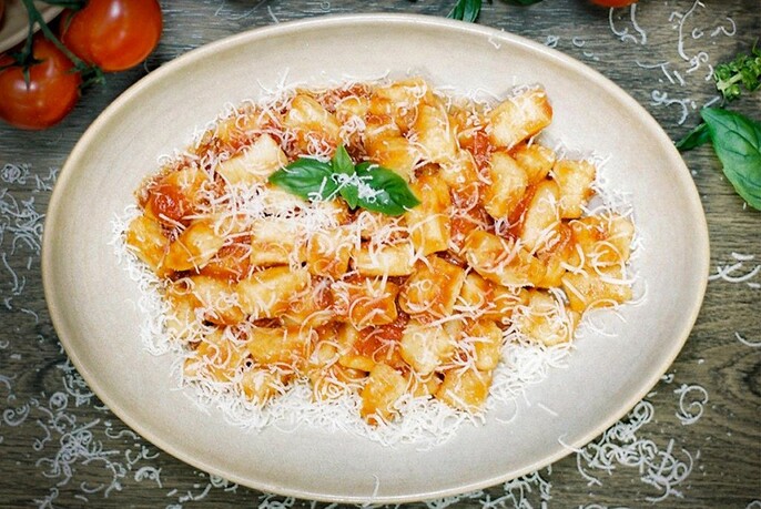 Bowl of gnocchi in tomato sauce with grated parmesan.