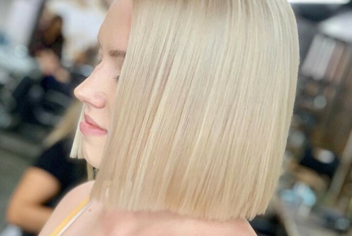 Side view of a blonde woman with a blunt bob haircut. 