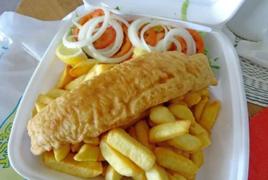 Serve of fish and chips with salad in a polystyrene container.