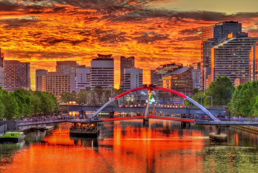 An image of the Melbourne skyline taken from the Yarra river, bathed in an orange sunset glow.