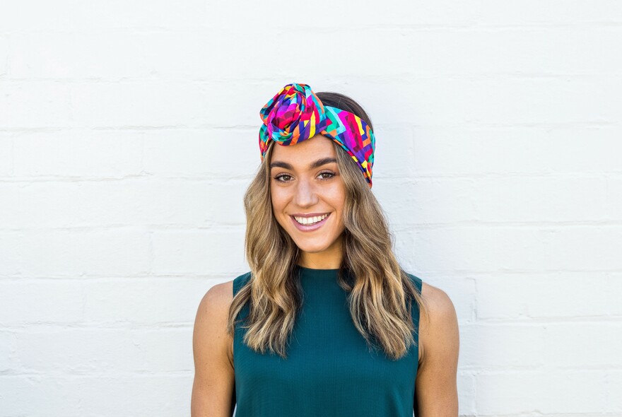 Woman with brightly-coloured headband and emerald green top.
