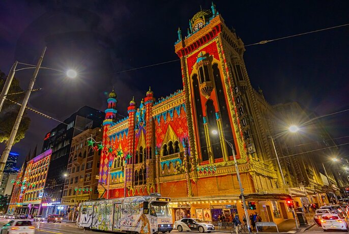 The facade of the Forum Theatre on Flinders Street illuminated with red and gold Christmas themed projections.