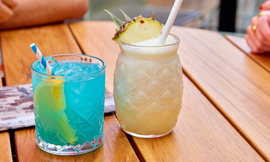 A pina colada and a blue cocktail on a table.