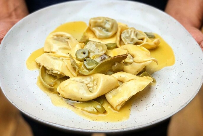 Bowl of filled pasta in yellow sauce.