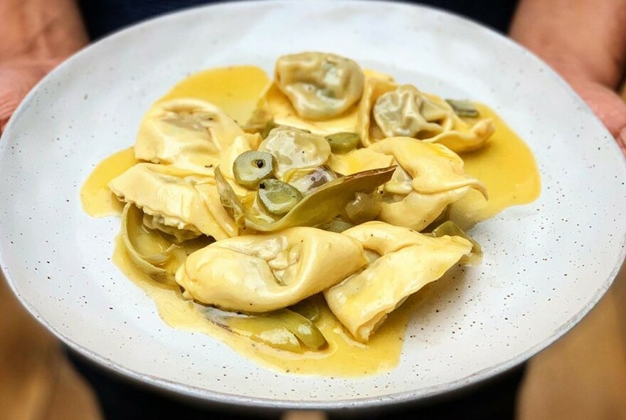 Bowl of filled pasta in yellow sauce.