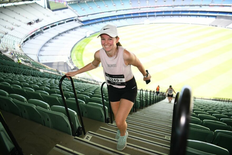 Stair runner climbing to the top of the grandstand steps with the MCG oval in the background.