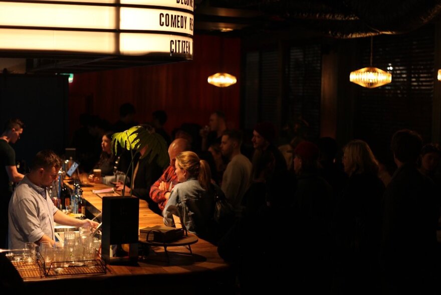 The dimly lit bar at Comedy Republic, with people lined up waiting to be served drinks.