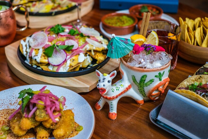 A table set with Mexican dishes and a cocktail in a donkey mug.