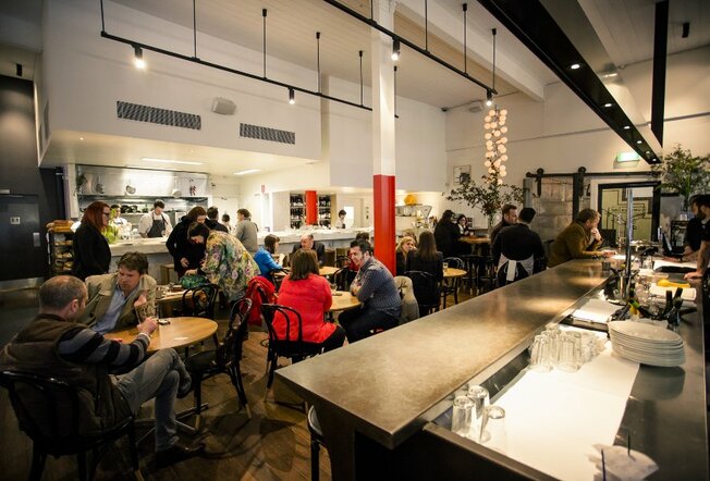 A busy restaurant with an open kitchen and industrial design
