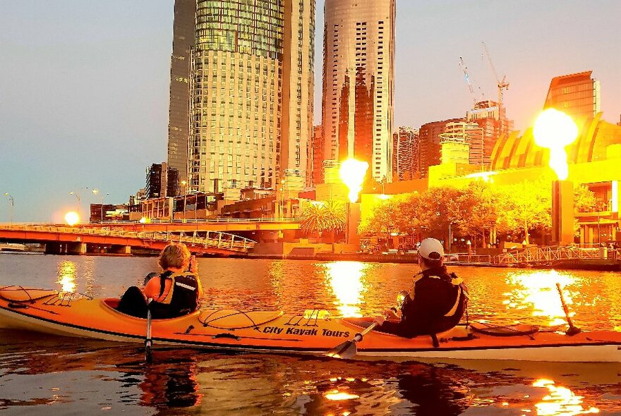 Timed fireballs erupting at Southbank at sunset as kayakers look on from the water. 