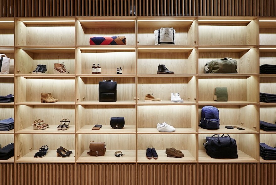 Lit wooden compartment shelves showing various APC Store wares.