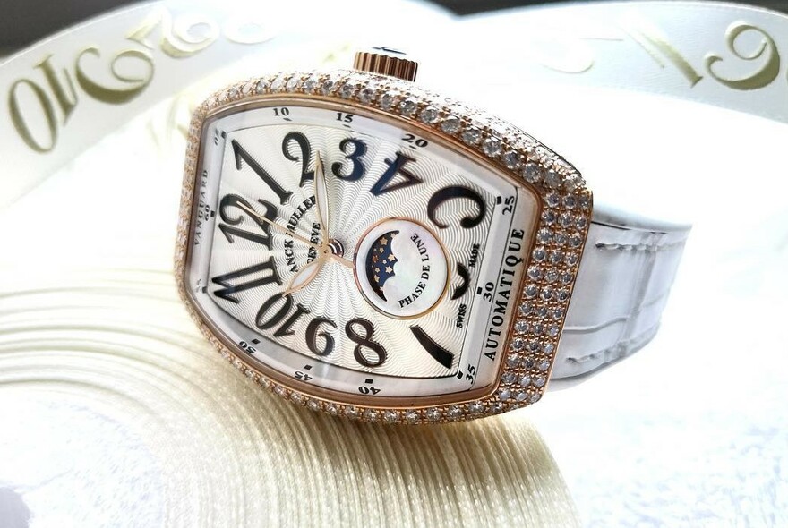 Ladies watch with elongated face, black numerals and diamond frame.