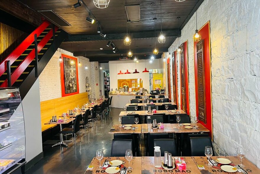 The interior of a small restaurant with feature red accents in the interior and a long yellow banquette.