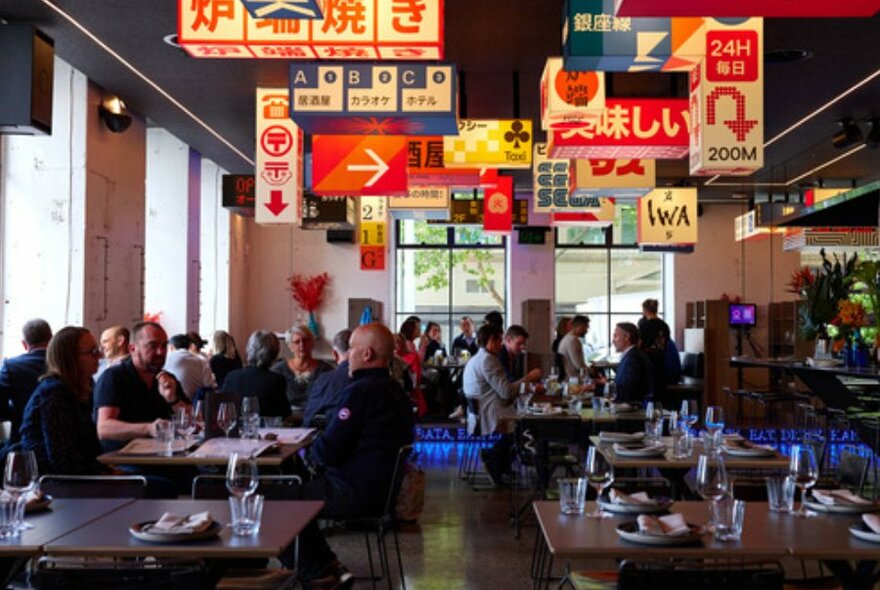 Wide shot of groups of people dining under unique Japanese signs.