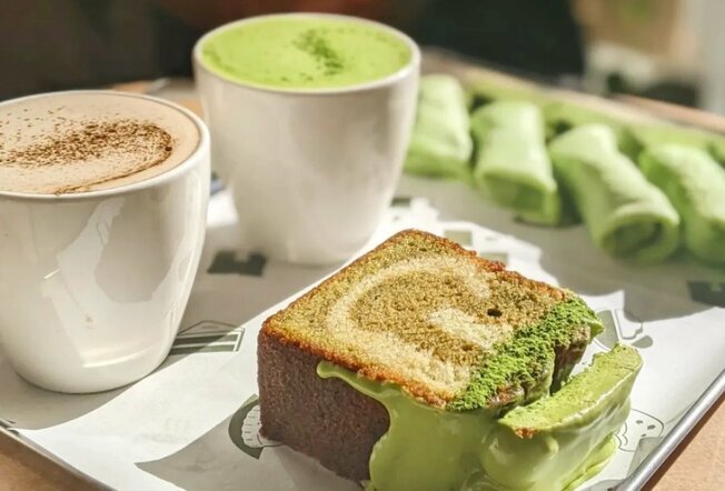 A cafe table with green cake, coffee and a matcha latte.