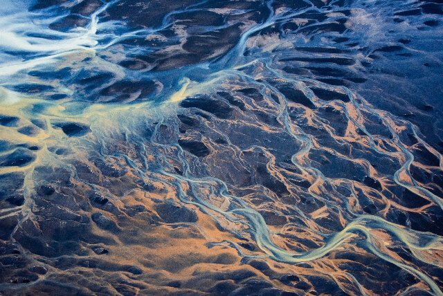 Aerial view of a river bending and winding its way over a mountainous landscape.