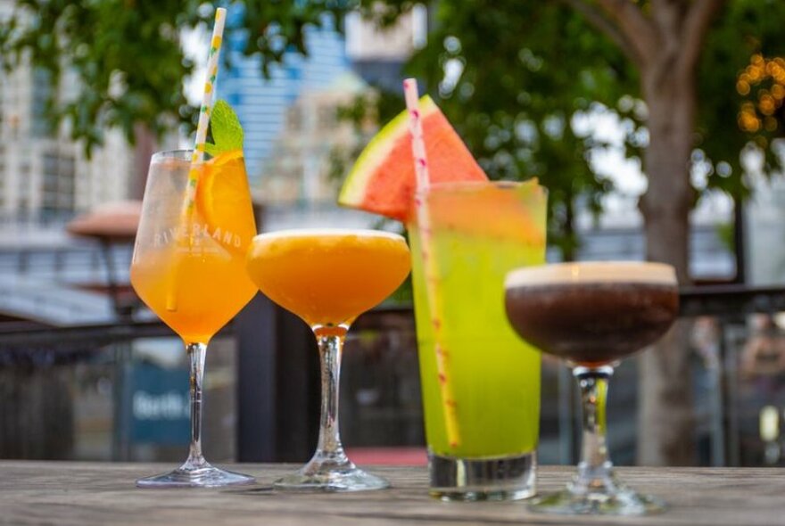 Four colourful cocktails outside a bar