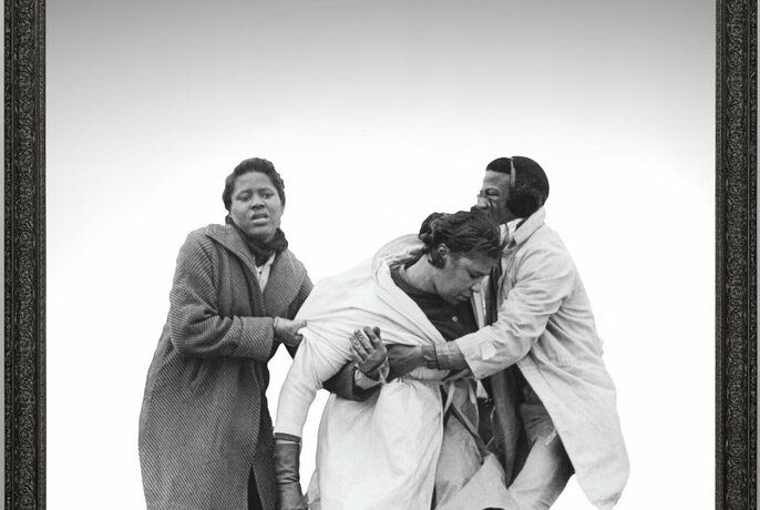 Two people supporting a woman under her arms, who appears to be slumping or falling as if fainting; a black and white image