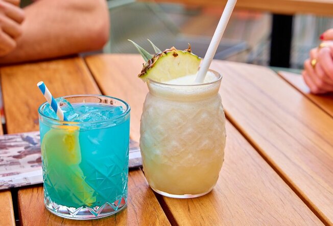 A pina colada and a blue cocktail on a table.
