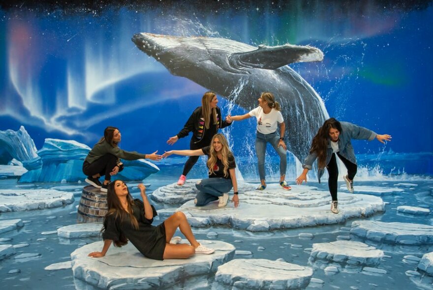 People posing and fooling around against a fantasy aquatic backdrop and floor with a whale breeching in the background. 