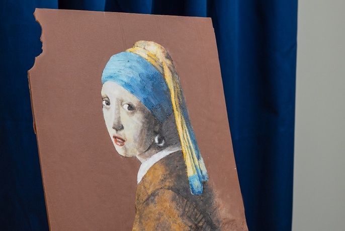 A block of chocolate with a bite taken from the top corner, and a Vermeer style girl with a pearl earring illustration on the front of the block.