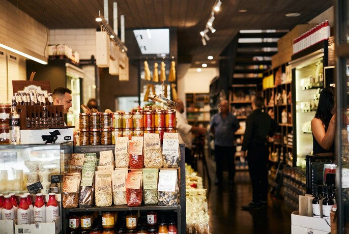 Interior of DOC Delicatessen showing many different products available and two men standing in the shop. 