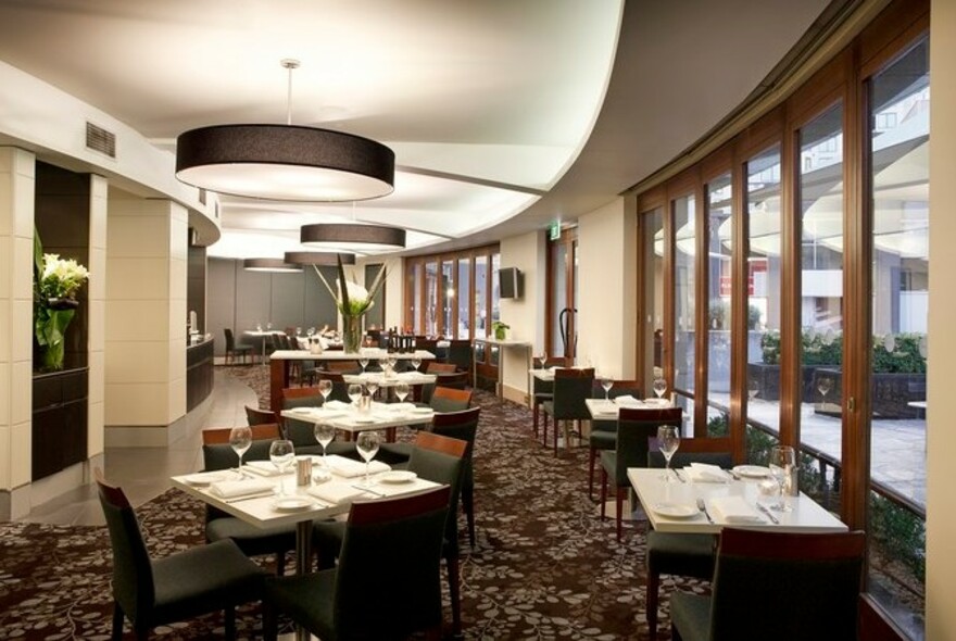 Jarrah Restaurant interior with dining tables on patterned carpet lit by large circular pendant lights.